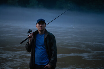 Man fishing on the mountain river at evening