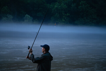 Man fishing on the mountain river at evening