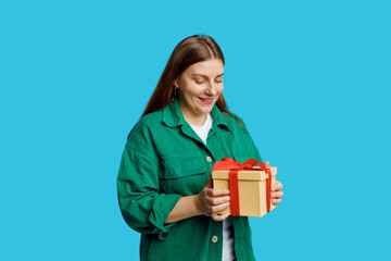 Portrait of cheerful, happy 30s woman receive gift, smiling excited. Girl holding wrapped present, celebrating birthday on blue background. Valentine's Day Women's Day birthday holiday concept.