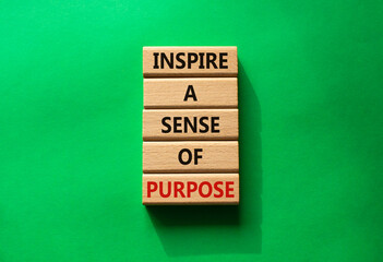Purpose symbol. Wooden blocks with words Inspire a sense of Purpose. Beautiful green background....