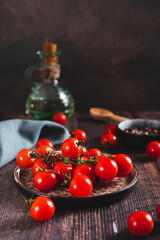 Branch of fresh ripe cherry tomatoes on a plate on the table vertical view