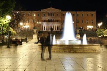 Syntagma Square in Athens, night view, blurred people, fountain, building of Parliament 