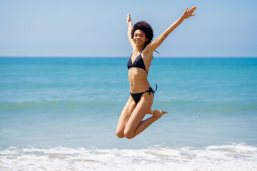 Active woman in bikini jumping near sea