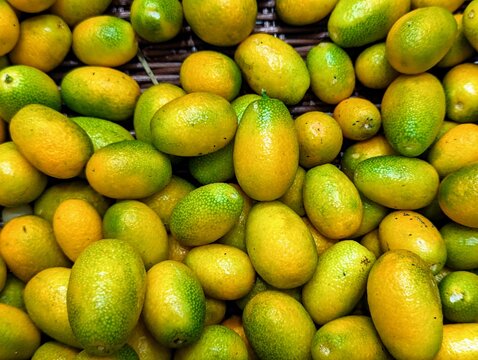 Cumquats, sometimes referred to as Kumquats, on display at a local supermarket. Some fruits are not perfectly ripe and still green.