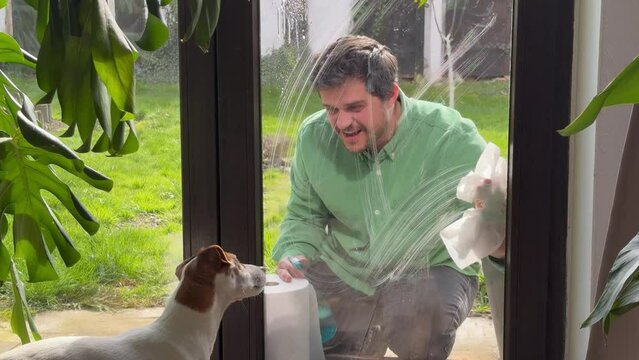 man wipes window at home with tissue and  leaner spray