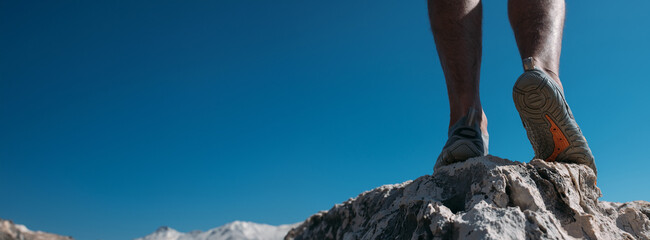 Protective swimming shoes on men's feet.  Close-up. Men's feet in stylish sports water slippers on the rocky seashore.