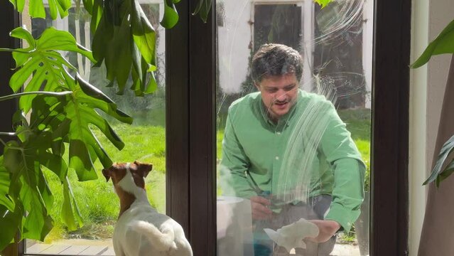 man wipes window at home with tissue and  leaner spray