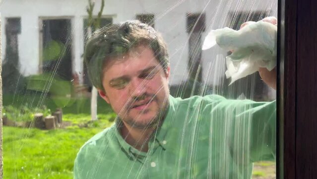 man wipes window at home with tissue and  leaner spray