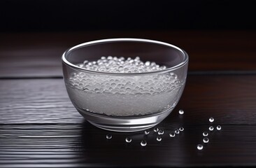 Round vessel with transparent plastic granules on wooden table