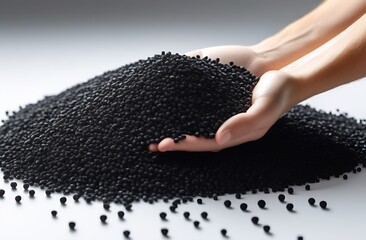 Hands with black plastic granules on white background