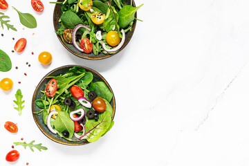 Fresh green spring salad on white marble table top view, healthy diet food concept.
