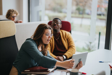 Focused professionals in a lively discussion at the office, with digital tablet and documents on table, in a modern workspace setting.