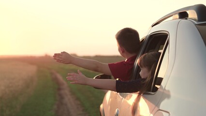 happy children boy girl leaning out car window waving arms, cheerfully leads wind hand, window,...