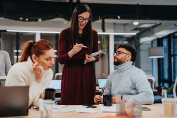 Young professionals collaborate and strategize in a corporate office. They discuss financial...
