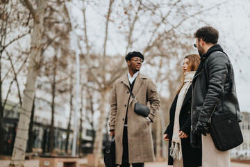 Three young business teammates engage in a discussion while walking outdoors in an urban setting, showcasing remote teamwork.