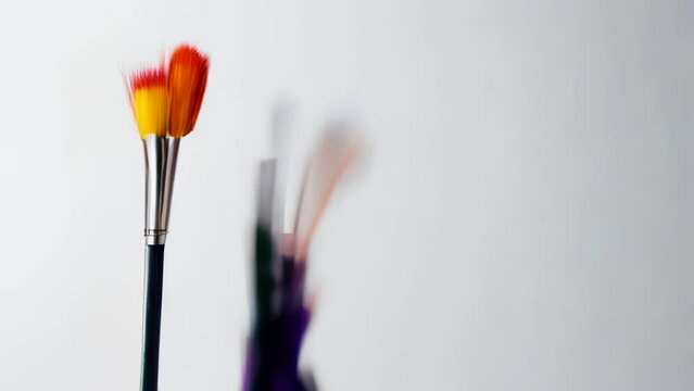 An array of paintbrushes with vividly colored tips stands poised for creation, representing the spectrum of possibilities in the artistic journey.