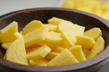 Raw sliced potatoes in a rustic wooden bowl