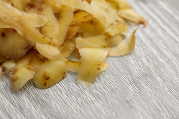 Pile of fresh potato peelings. Kitchen garbage on a wooden cutting board