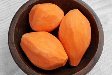 Raw whole organic peeled sweet potatoes in wooden bowl. Fresh vegetable root