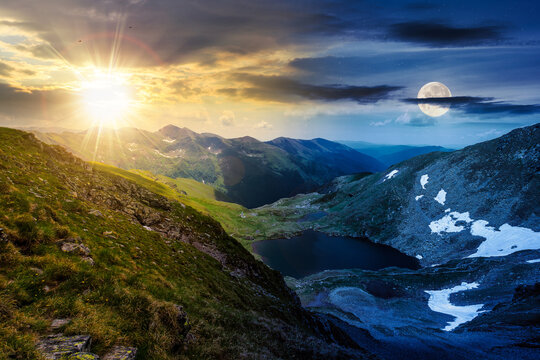 summer solstice in mountains of romania. beautiful landscape with capra lake and snow on the hills beneath a sky with sun and moon. day and night time change concept