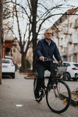 Active senior man enjoying a bike ride in urban setting during autumn.