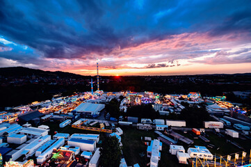 A breathtaking sunset envelops a bustling carnival, its lively atmosphere highlighted by the...