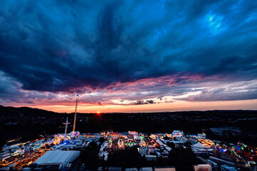 A breathtaking sunset envelops a bustling carnival, its lively atmosphere highlighted by the...