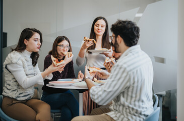 Young group of business people enjoying a break, eating pizza together at a table in their workplace.