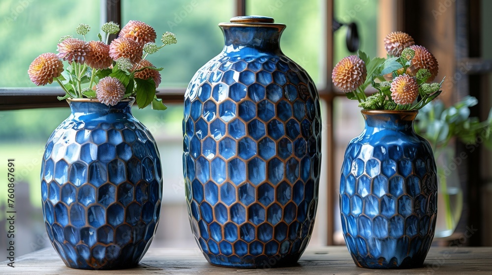 Poster three blue vases with flowers in them sitting on a table next to a window with a view of a field.