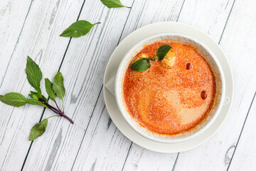 Thai spicy tom yum soup on a white wooden background with thai basil