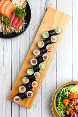 top view of japanese maki sushi rolls on a white wooden background