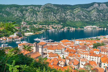 Aerial view of Kotor old town with orange rooftops and marina in Kotor bay with boats and yachts, Montenegro. Summer vacation resort on Adriatic fjord in summer day. Travel destination