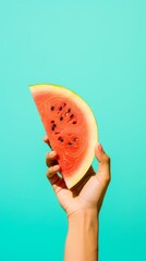 Summer Vibes: Hand Holding Fresh Watermelon Slice on Aqua Background