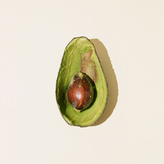 Emptied shell of an avocado and seed avocado with copy space on beige background. Sliced fresh ingredient