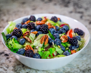 Colorful bowl of salad with pecans, blueberries, and  blackberries