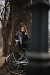 Fototapeta na wymiar Confident young woman, business attire paired with a classic bike, exudes elegance and style in a natural setting.