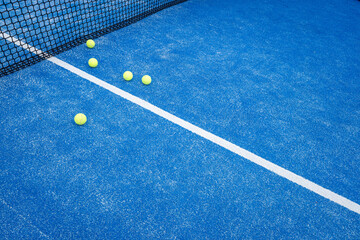 Five balls near the net in a blue paddle tennis court, racket sports concept