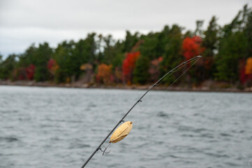 Fall colors on a cloudy Lake with a fishing rod in the foreground