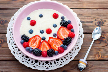 Greek yogurt bowl with fresh berries, strawberry, raspberry, blueberry on natural wooden background, top view