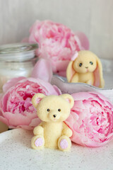 Cute edible teddy bear toy made of white chocolate with fresh peonies and candles on the...