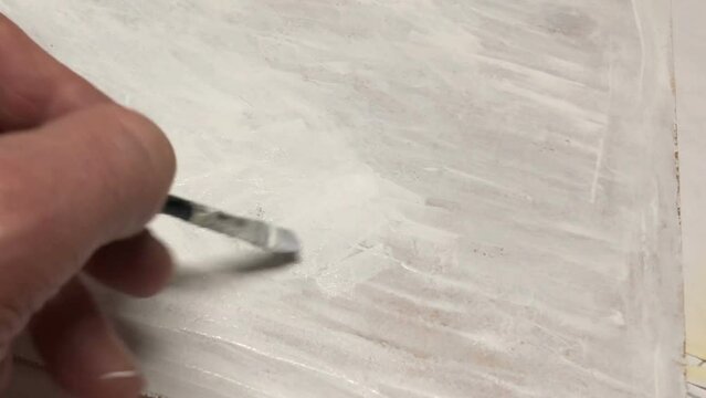 artist priming canvas, human hand with brush, close-up