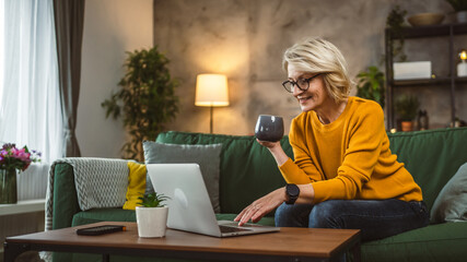 Mature blonde caucasian woman use laptop computer at home for work
