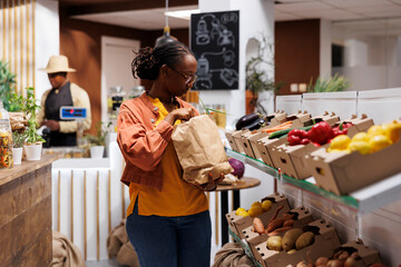 African American woman explores a modern eco friendly grocery store, browsing a variety of fresh,...