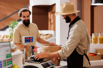 Middle eastern salesman being of service to caucasian customer at checkout counter. At cashier...