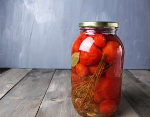 Canned food. Salted tomatoes in a glass jar on a gray background with space for copy space text. Homemade preparations