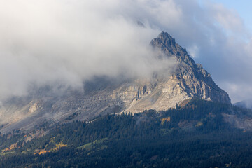 A mountain covered in clouds with a rocky peak