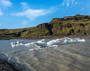 Sólheimajökull picturesque glacier in southern Iceland. The tongue of this glacier slides from the volcano Katla. Beautiful glacial lagoon with blocks of ice and surrounding mountains.