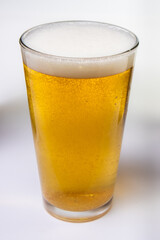 A glass of beer is full and has foam on top