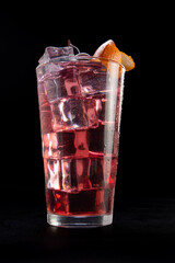A glass of pink drink with ice cubes and an orange slice on top