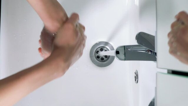 Young man washing hands in bathroom at home, Coronavirus hand washing for clean hands hygiene. Top view